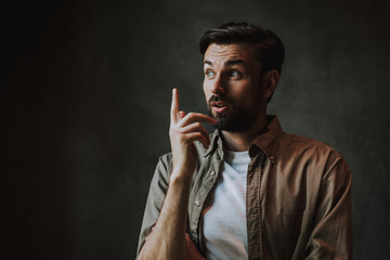 Portrait of thoughtful bearded man gesticulating hand while having interesting idea. He isolated on dark background