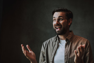 Portrait of outgoing bearded man with attractive smile gesticulating hands while expressing...