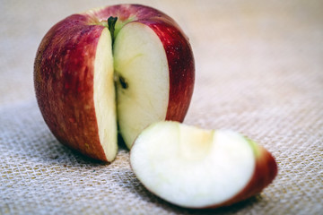 Red apple next to slices of another apple.