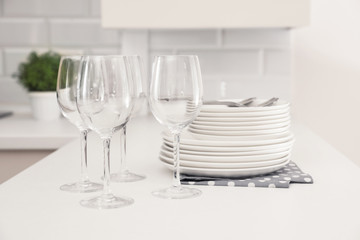 Stack of clean dishes and glasses on table in kitchen