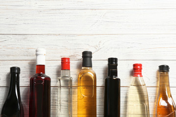 Flat lay composition with different kinds of vinegar in bottles and space for text on wooden...