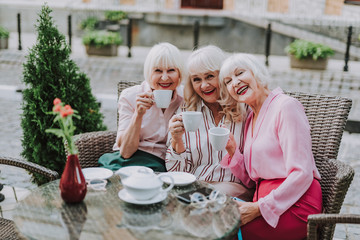 Waist up photo of stylish female at the table. White-haired women sitting on the couch and holding...