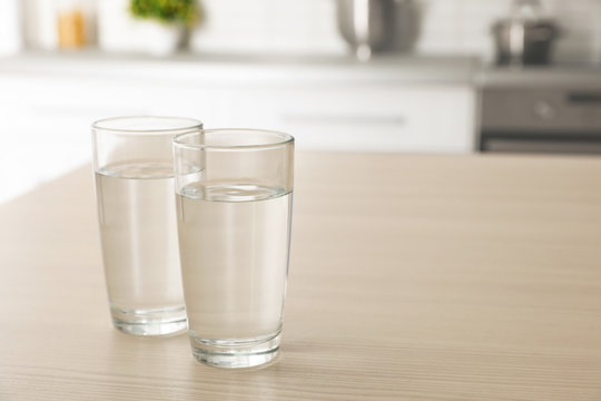 Glasses of fresh water on table indoors. Space for text