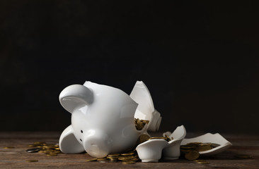 Broken piggy bank with money on table against dark background