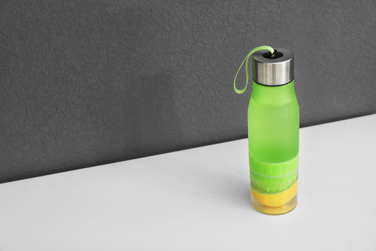 Sport Bottle With Lemon Water On Gray Background. Space For Text