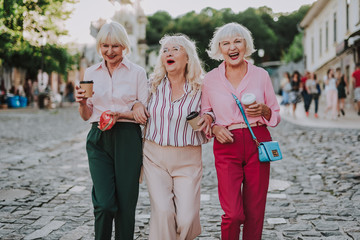 Waist up photo of old stylish women. White-haired females holding each other and laughing
