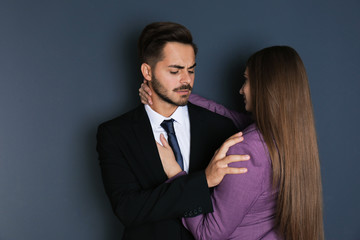 Woman molesting her male colleague on dark background. Sexual harassment at work - obrazy, fototapety, plakaty