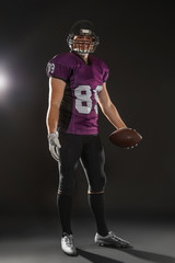 American football player with ball on dark background