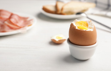 Holder with soft boiled egg on table. Space for text