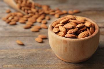 Tasty organic almond nuts in bowl on table. Space for text