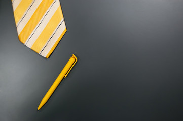 pen and tie in yellow on gray background