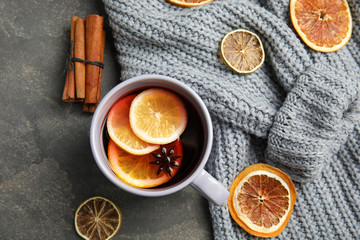 Flat lay composition with cup of hot winter drink and warm knitted sweater on gray background. Cozy season