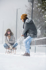 Young couple with sled playing in snow in nature