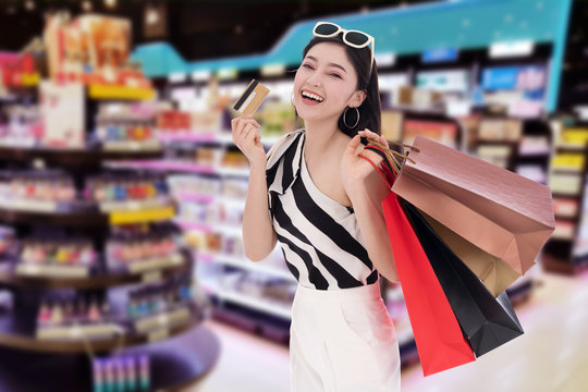 woman holding credit card and shopping bag at mall
