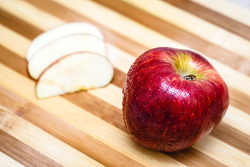 Red apple next to slices of another apple.