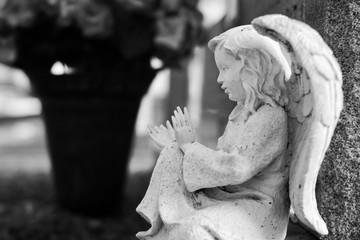 Black and white image of an angel statue in a cemetery.