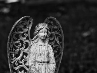 Black and white image of an angel statue in a cemetery.
