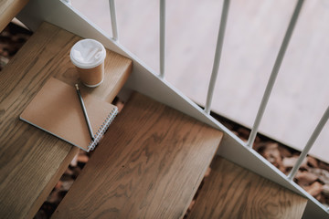 Close up of hot beverage and notepad on wooden stairs