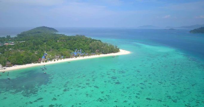 High altitude aerial panoramic slow pan view of colorful tropical coral reef, emerald green sea waters off Sunrise beach and overview of Thai island, Ko Lipe, Thailand. 4k 1.9:1 23.976fps