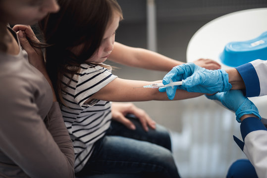 Concept of professional immunizations in healthcare immune system. Top view of female child on mother hands in process of being vaccinated