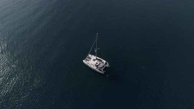 Aerial view from a great height on a white modern catamaran without sails in the sea.