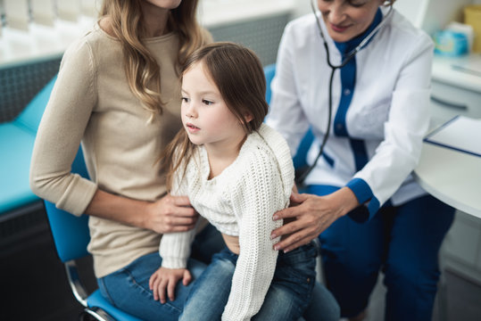 Concept of professional consultation in therapist practice. Full length portrait of pediatrician woman examining girl by stethoscope in medical office