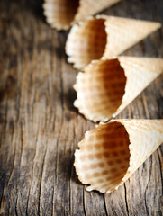 Sweet wafer cone for ice cream on wooden background.