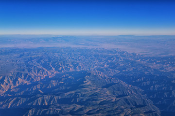 Aerial view of topographical Rocky Mountain landscapes on flight over Colorado and Utah during autumn. Grand sweeping views of rivers, mountain and landscape patterns. Top view, Rockies and Wasatch Fr