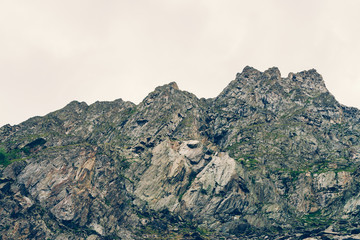Giant ridge under cloudy sky. Misty rocky mountainside with vegetation. Amazing mountain range in...
