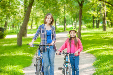 Fototapeta na wymiar Mom and daughter are cycling in the park together