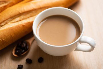 Cup of coffee and baguette french bread on wooden table in the morning
