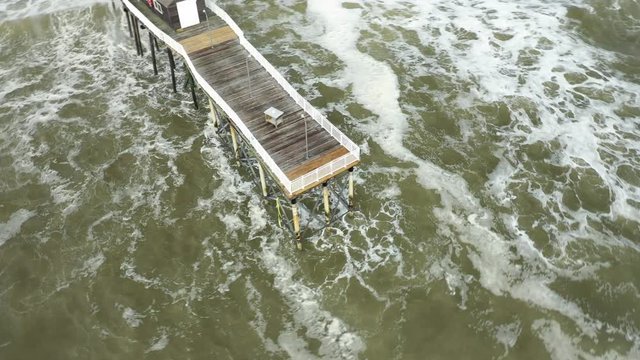Waves are hitting a pier at the beach of Belmar.