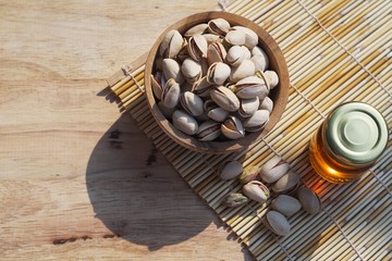 Pistachio in wooden bowl on wood table with green banana leaf background, copy space