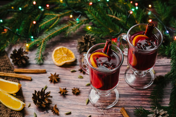 Two glasses of Christmas mulled wine with spices and orange slices on a wooden rustic table. A traditional drink for the winter holidays