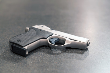 Small Silver Handgun Isolated on Dark Table