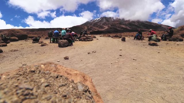 Static shot of a group of people trekking, towards the summit of mount Kilimanjaro, carrying stuff on their head, on a sunny day, near Horombo hut, in Tanzania, Africa