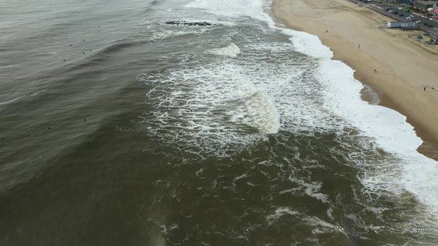 Birds fly over the ocean and surfers are waiting for waves.