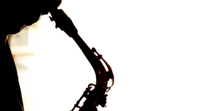 Silhouette of an old man playing the saxophone against a white background