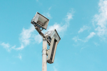 Electric spotlight pole on the street with blue cloudy sky background