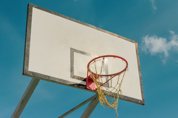 Naklejka premium White basketball shield on the playground on background of blue sky
