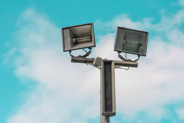 Electric spotlight pole on the street with blue cloudy sky background