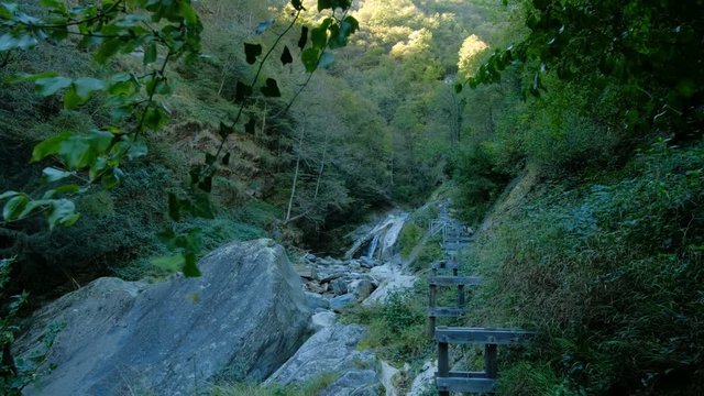 Glide shot overlooking a ruined town area and small waterfall in the village of Corippo in Switzerland. Smooth slide camera motion shot in 4K.
