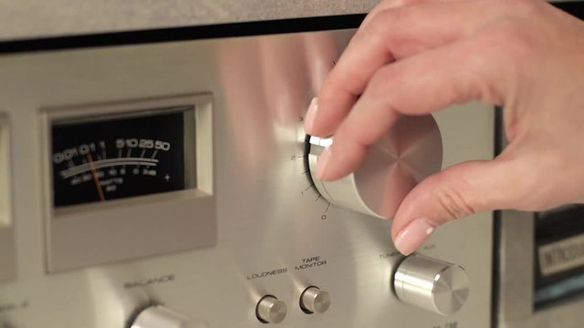 Close up of woman's hand turning volume knob in clockwise direction,  static locked down footage.