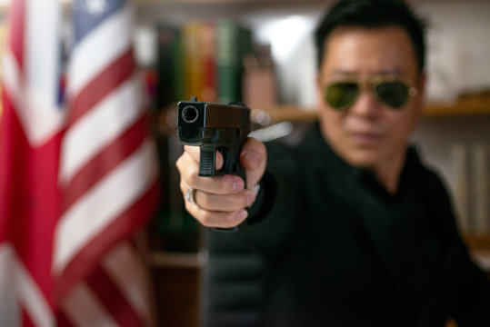 A man holding a gun in hand, over blurred background of US Flag