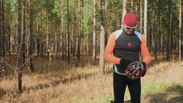 Training an athlete on the roller skaters. Biathlon ride on the roller skis with ski poles, in the helmet. Autumn workout. Roller sport. Adult man riding on skates. The athlete puts on skis and a