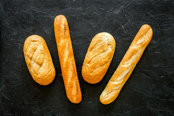 Loaf of white bread and baguette on black background top view copy space