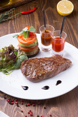 Fried juicy beef steak served with grilled vegetables and spicy sauces