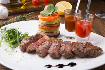 Fried juicy beef steak served with grilled vegetables and spicy sauces