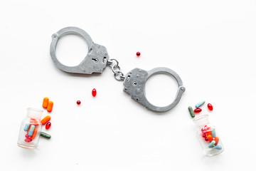 Arrest for illegal purchase, possession and sale drugs concept. Drugs as pills near handcuff on...