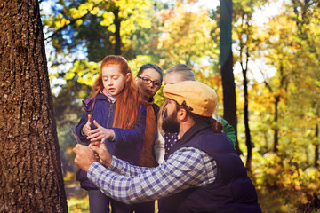 Smart teacher. Positive good looking man talking to children while holding a digital device